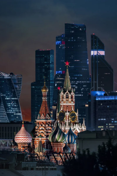 Вид на деловой центр «Москва-Сити» через башни Московского Кремля на закате